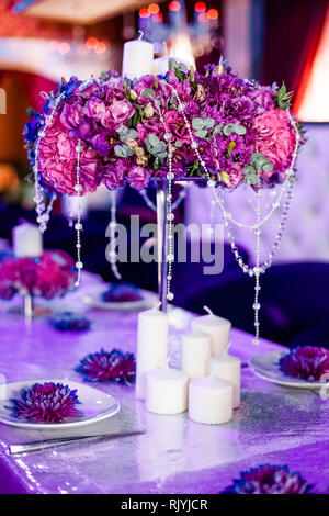 Wedding party table flowers and white candles on the table. Pink pions and wite chrysanthemums bouqet with shining decor. Stock Photo