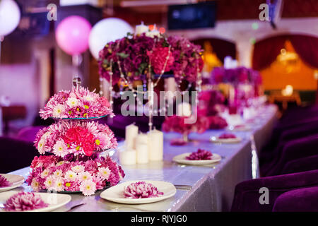 Wedding party table flowers and white candles on the table. Pink pions and wite chrysanthemums bouqet with shining decor. Stock Photo