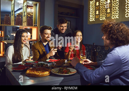 Happy friends talk in a restaurant in the evening.  Stock Photo