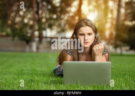 Woman being angry and holding fist in air looking at computer Stock Photo