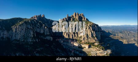 Aerial; wide panorama of famous abbey homonymous mountain range Montserrat; tourist attractions route of Spain; drone view of steep stone slope with m Stock Photo