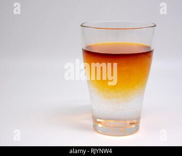 A glass of clean water, with orange brown spots. Painted with iodine. Stock Photo