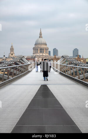 People are walking towards St Paul's Cathedral across the Millenium footbridge. The bridge spans the River Thames in London, England near Tate Modern.