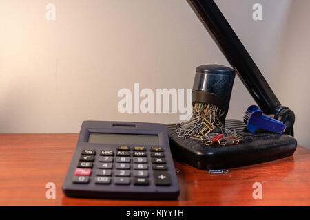 Office desk with calculator, desk lamp and paper clips in the background - image Stock Photo