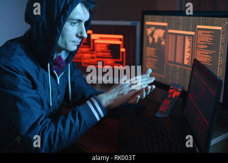 Male hacker celebrates success with a hand gesture. A successful attempt at system hacking and data theft. The concept of cybersecurity Stock Photo