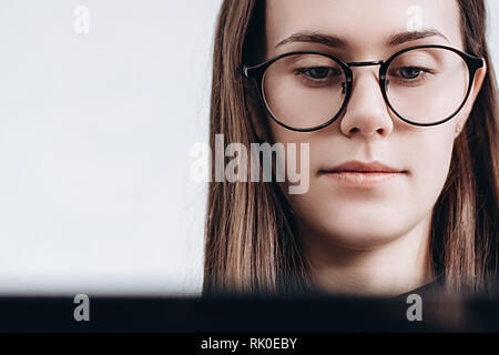 Girl in the glasses is working on a portable computer at home. Stock Photo