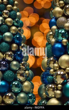 Orange colored bokeh lights with blue Christmas tree baubles in the foreground giving it an abstract look. Stock Photo