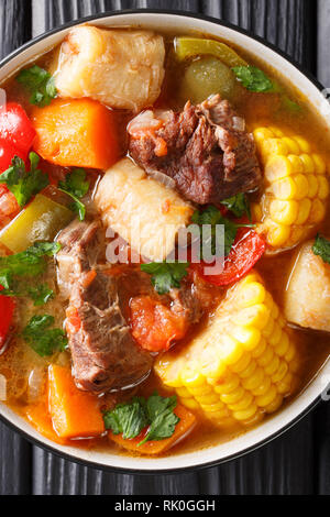 Sancocho Recipe a hearty and absolutely delicious stew made with meat, vegetables and spice close-up on a plate on the table. Vertical top view from a Stock Photo