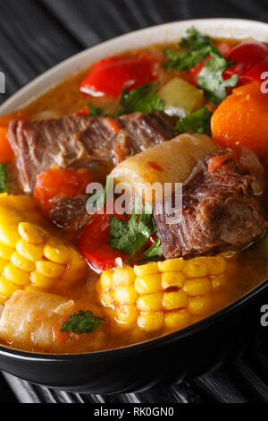 Sancocho Recipe a hearty and absolutely delicious stew made with meat, vegetables and spice close-up on a plate on the table. Vertical Stock Photo