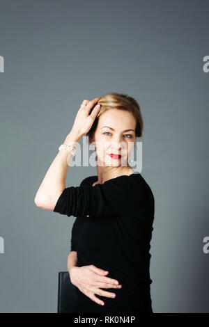 Portrait of beautiful woman in a black dress against grey background Stock Photo