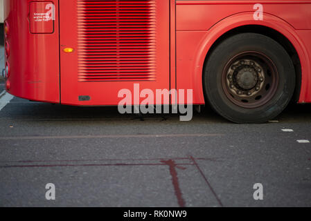 The rear wheel of a double decker red London bus traveling along a road ...
