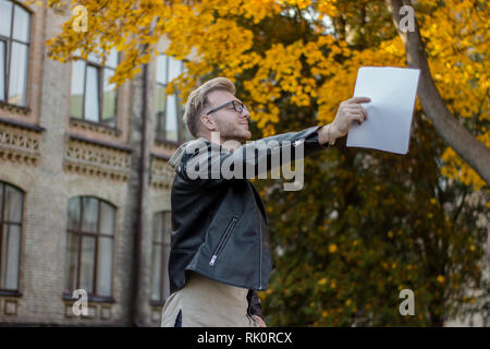 Happy smart student in casual clothes holds papers and looks away Stock Photo