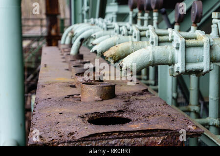 old boiler room in basement. Old control center in boiler room with pipes and round water taps. Abandoned interior of an industrial building. old dama Stock Photo