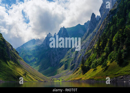 Mountain landscape in the Swiss Alps with jagged peaks and a pristine blue mountain lake in the valley far below. Stock Photo