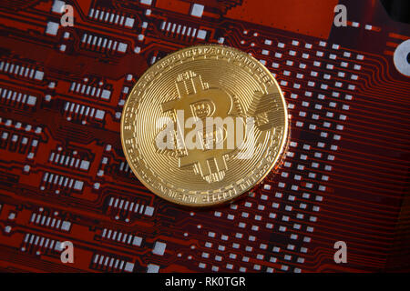 Bitcoin gold coin on a orange or red & black computer flexible circuit. Stock Photo