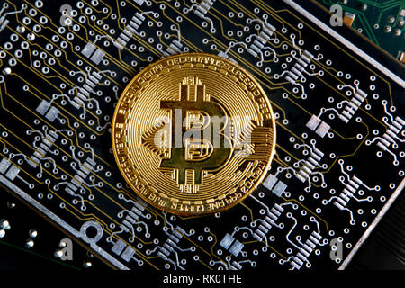 Bitcoin gold coin on a silver, grey & black computer flexible circuit. Stock Photo