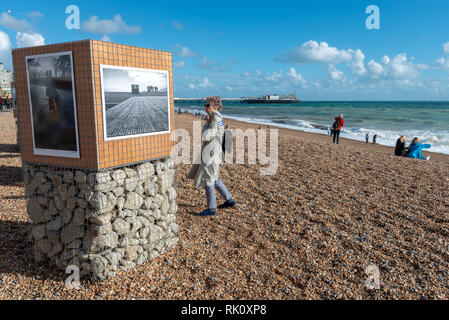 A women looks at a photograph displayed on the beach during the Brighton Photo Fringe 2016 - Tides Exhibition, Brighton, Sussex, UK. Stock Photo