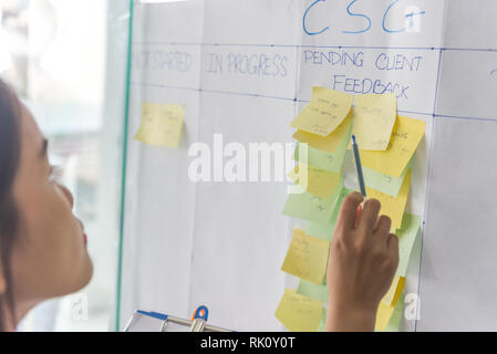Woman reading client feedbacks on the sticky hat Stock Photo