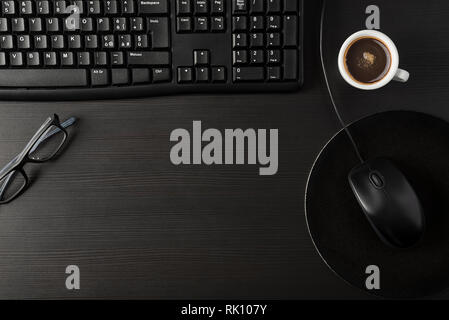 Total black desk with desktop and cup of coffee Stock Photo