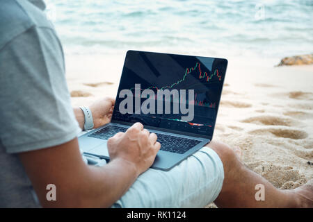 Freelancer Work by Laptop on Tropical Beach. Young Man use Computer during Summer Vacation. Successful Happy Businessman Relax on Sand with Gadget in  Stock Photo