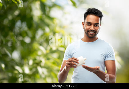 happy indian man applying lotion to his hand Stock Photo