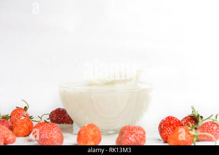 A sweet scented sweet strawberry falls into milk Stock Photo