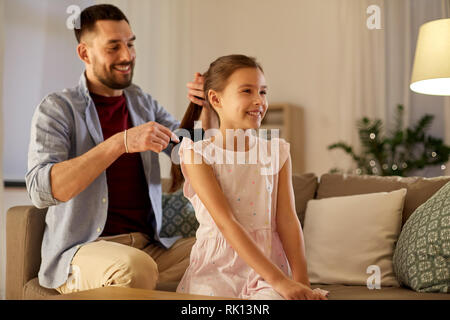 father brushing daughter hair at home Stock Photo