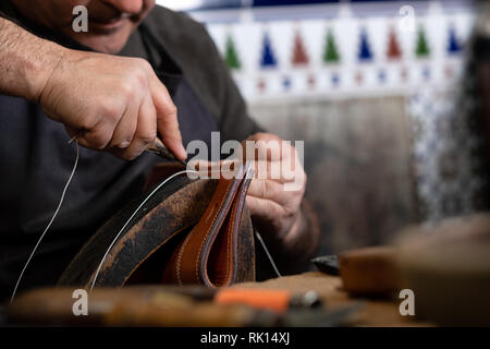 craftsman sewing piece of leather with special needle Stock Photo