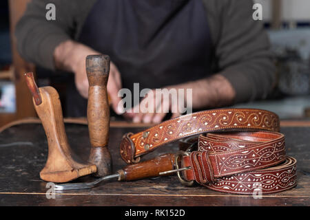 leather belts with leather craftsman tools on table Stock Photo