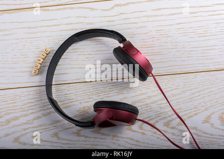 Dice-sized alphabet cubes spelling music and red headphones on wooden background Stock Photo