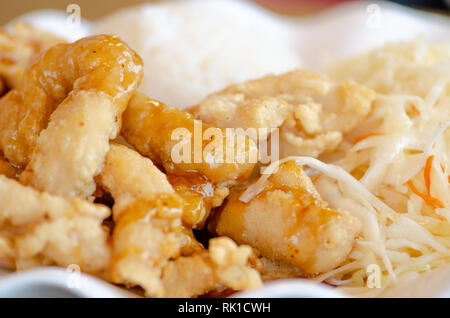 Chinese food, rice with fried chicken in soy sauce and vegetables, cabbage and carrots in a white plate, close up Stock Photo