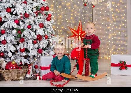 Christmas two children boys posing in studio shoot close to new year tree wearing velvet green and red clothes Stock Photo