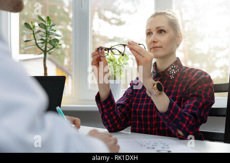 eye care - woman testing her new eyeglasses in optometrist office Stock Photo
