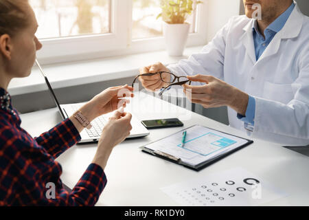 eye health - optician gives new eyeglasses to female patient Stock Photo