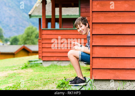 Portrait of boy sitting on steps of holiday chalet, Flam, Norway, Europe Stock Photo