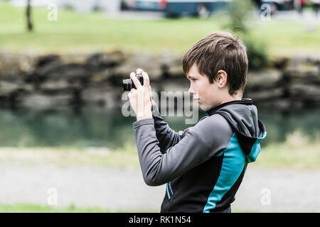 Young boy looking through lens of digital camera, creativity and focus Stock Photo