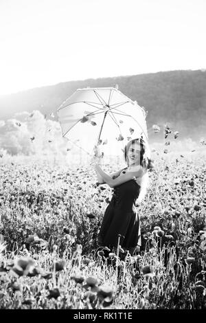 pretty happy girl in field of poppy seed with umbrella Stock Photo