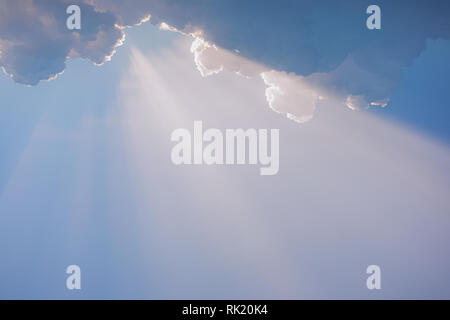 Beautiful peaceful early morning sky with soft charming white straight real sunrays from over fluffy white clouds isolated on blue heaven background.  Stock Photo