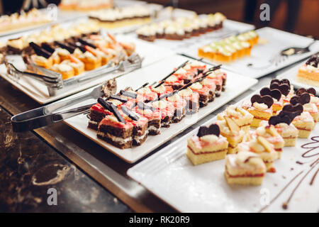 Assortment of fresh desserts displayed in hotel buffet. Variety of cakes in canteen ready for dinner Stock Photo