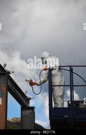 Tradesman spray paints the steel beams on a construction site Stock Photo