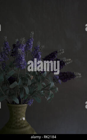 Decorative lilac bouquet in vase on dark grey tinted background Stock Photo