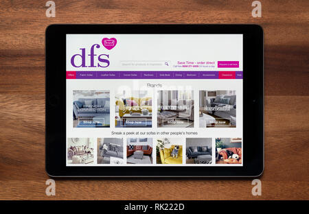 The website of dfs is seen on an iPad tablet, which is resting on a wooden table (Editorial use only). Stock Photo