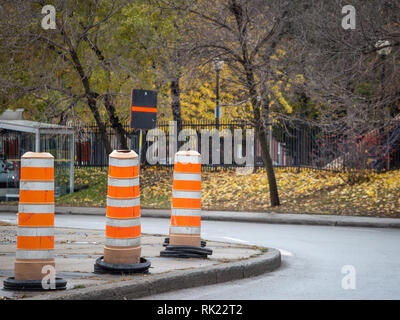 Construction barrels, north American style, on a renovation site on an asphalted street of downtown Montreal, Quebec, Canada. These plots are iconic o Stock Photo