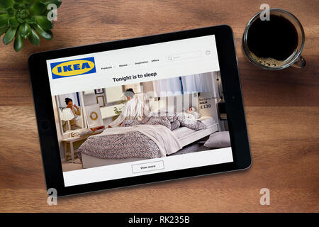 The website of Ikea is seen on an iPad tablet, on a wooden table along with an espresso coffee and a house plant (Editorial use only Stock Photo