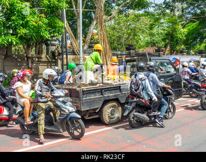 Traffic congestion motorcyclists riding around a work truck in Jimbaran, Bali Indonesia. Stock Photo