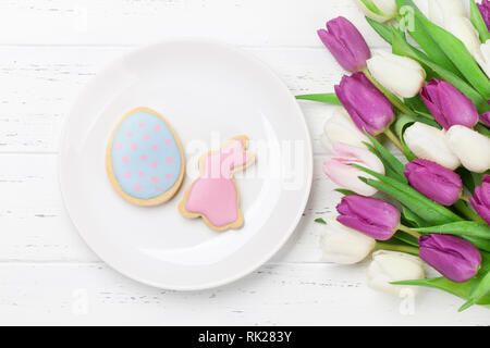 Easter greeting card with tulip flowers bouquet and cookies. Top view Stock Photo