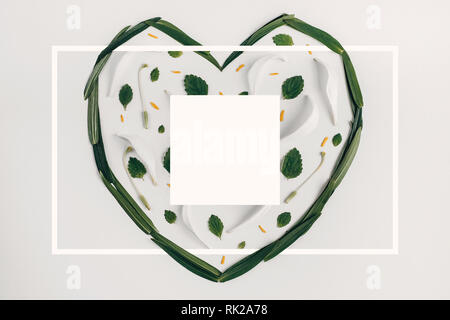 Leaves in the form of a heart. Creative layout made with leaves of white lily on bright background with a drawn frame. Spring minimal concept. Flat la Stock Photo