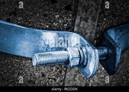 https://l450v.alamy.com/450v/rk2ddk/close-up-of-a-metal-bolt-shaft-with-spiral-screw-thread-and-hexagon-nut-on-a-concrete-pole-steel-bolted-joint-with-blue-hoop-on-dark-gray-background-rk2ddk.jpg