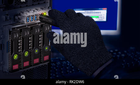 Hand in black glove holding USB flash drive. Computer data theft detail. Spy or saboteur is copying secret information. Server and hot-swap hard disks. Stock Photo