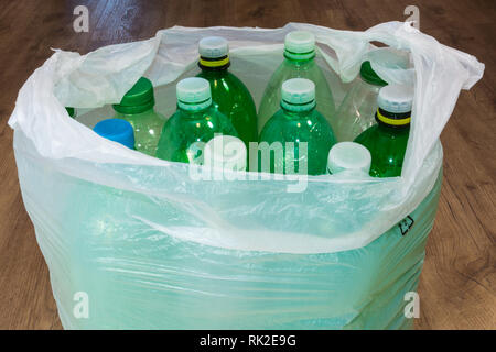 Detail of empty plastic bottles in a carrier bag on wooden floor. Ecological sorting and disposal of household waste. Contamination of e environment. Stock Photo